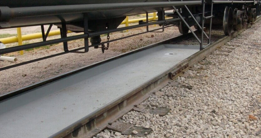 Fiberglass spill containment pan installed beneath rail transfer equipment