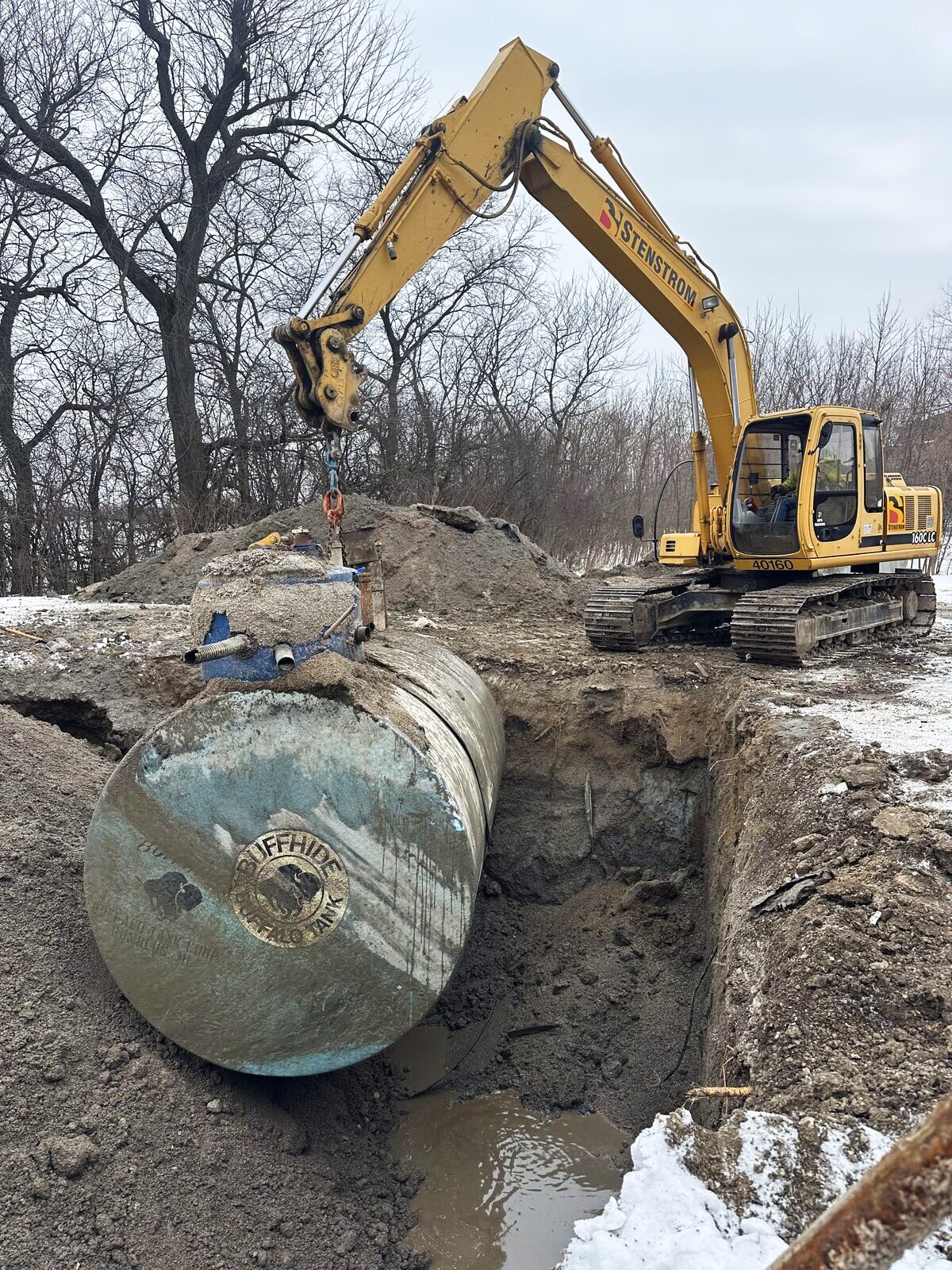 Excavator lifting an old underground storage tank from the excavation